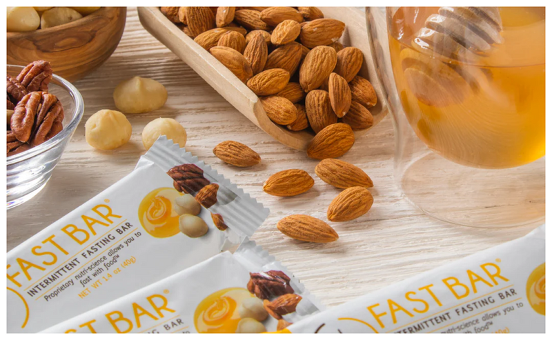 Prolon's Honey & Nut Fast Bars displayed on a table with honey & almonds, pecans and other nuts