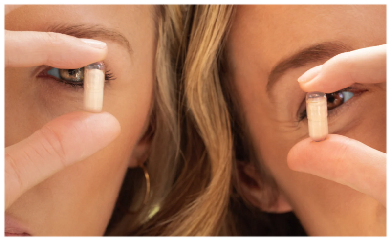 Two women each holding up a single L-Pill capsule from Prolon